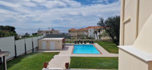 Η κρυστάλλινη πισίνα της Villa Memories με ξαπλώστρες και απεριόριστη θέα στη θάλασσα