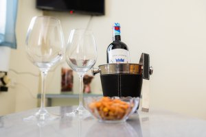 Μπουκάλι κρασί με δύο ποτήρια σε τραπεζάκι της Villa Memories για καλωσόρισμα επισκεπτών