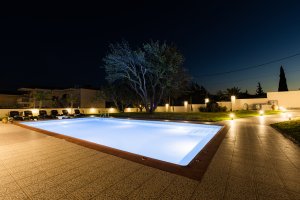 Πισίνα της Villa Memories με ξαπλώστρες και φωτισμό τη νύχτα στην Κινέτα