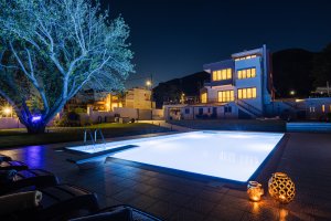 Φωτισμένη πισίνα της Villa Memories με θέα τη βίλα τη νύχτα στην Κινέτα