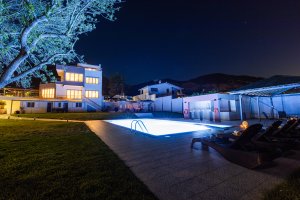 Ξαπλώστρες δίπλα στην πισίνα της Villa Memories με φωτισμό τη νύχτα