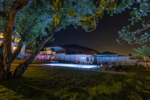 Πισίνα της Villa Memories φωτισμένη τη νύχτα με θέα τον κήπο