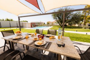 Εξωτερική τραπεζαρία της Villa Memories στην Κινέτα με τραπέζι φαγητού, πρωινό και θέα στην πισίνα