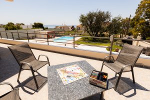 Εξωτερικό καθιστικό στη Villa Memories με τραπέζι και θέα την πισίνα και τον κήπο